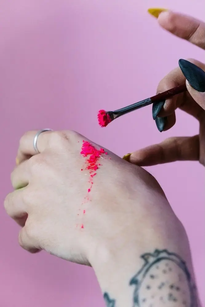 Person tester kreativt neonfarvet makeup på hånden – symbol på kreativitet og farverigt indhold, som bruges i TikTok-kampagner og visuel storytelling.